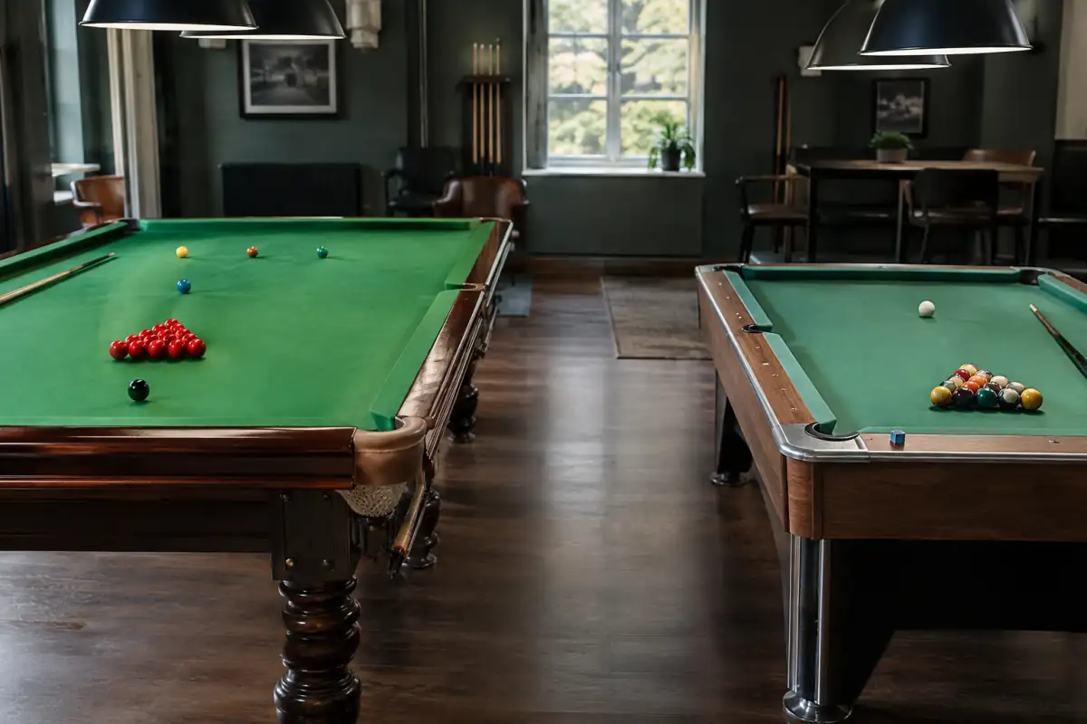 Table de snooker avec billes rouges et de couleur, à côté d’un billard américain avec un triangle de billes numérotées.