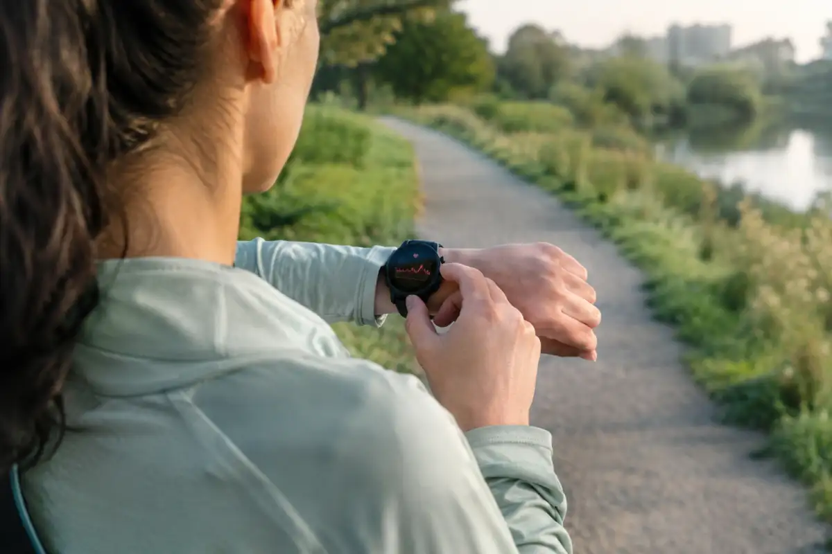 Un sportif consulte sa montre pendant une sortie facile en extérieur pour surveiller sa fréquence cardiaque.