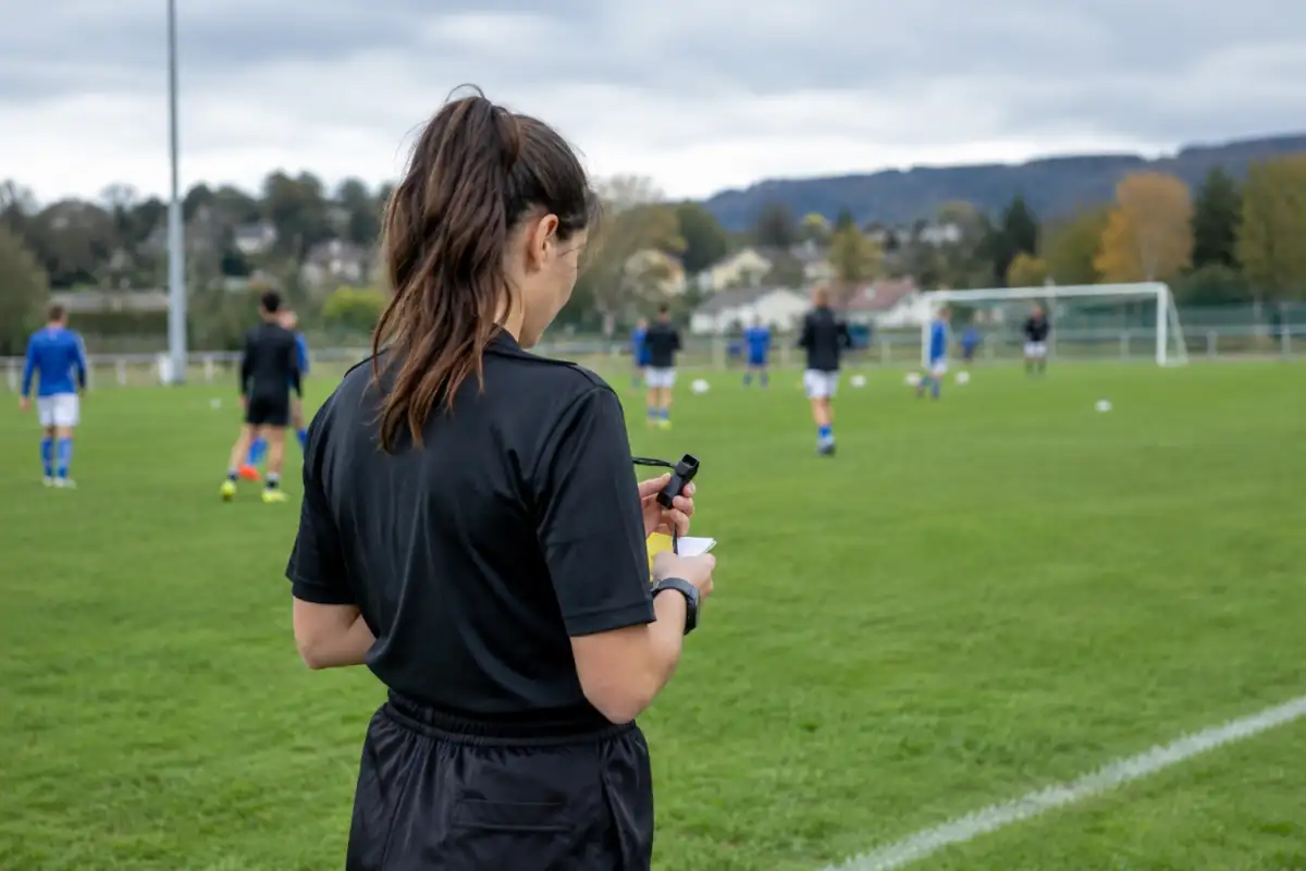 Arbitre amateur préparant son matériel au bord d’un terrain avant une rencontre sportive locale.