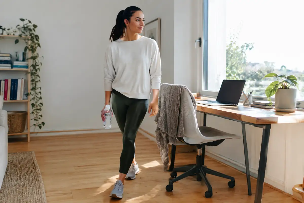 Une personne fait une courte pause de marche près de son bureau à domicile pour interrompre une longue période assise.