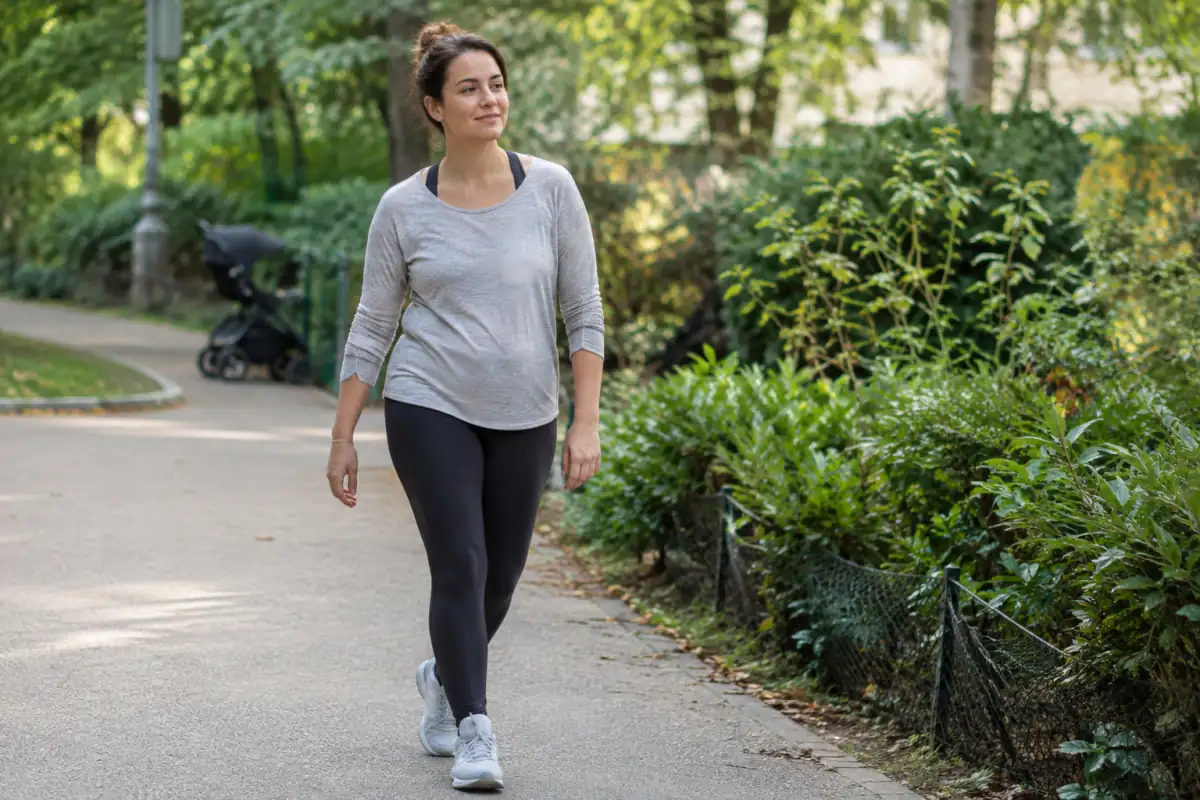 Jeune mère en tenue confortable reprenant une marche douce dans un parc après son accouchement.