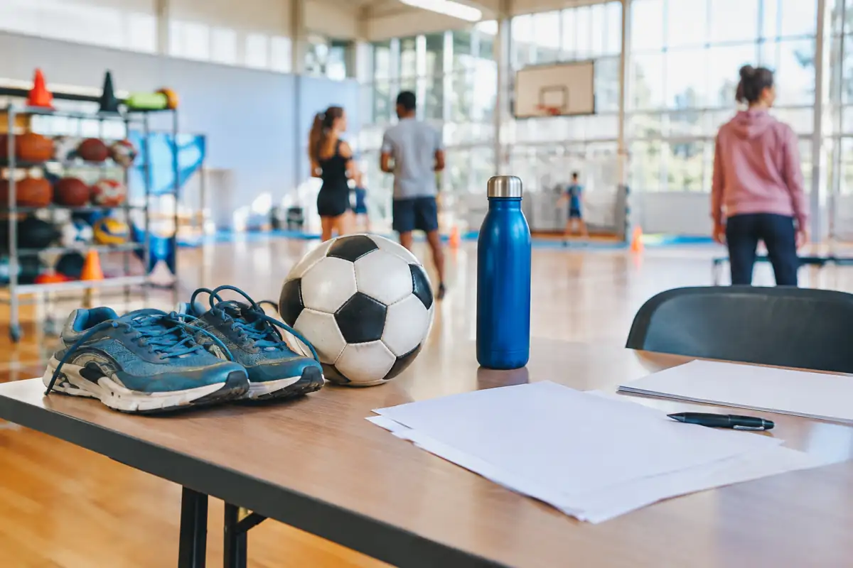 Équipement sportif et documents d’inscription posés sur une table, dans un club lumineux avant une séance.