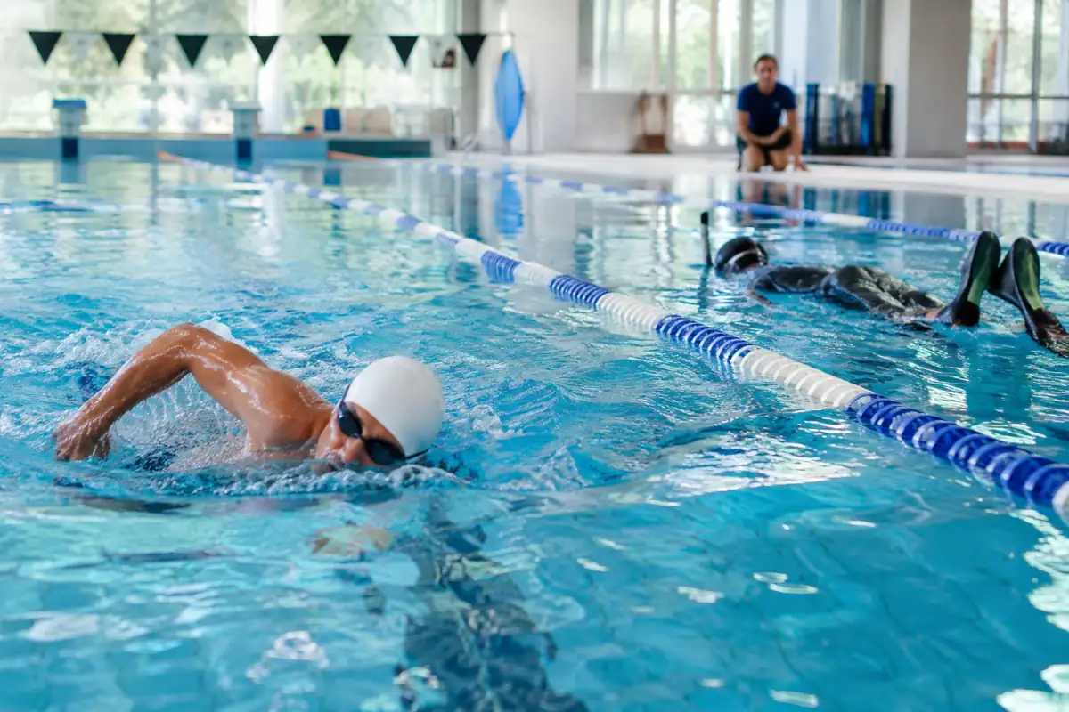 Nageurs s’entraînant en piscine, l’un en natation sportive et l’autre avec des palmes, pour illustrer les sports aquatiques.