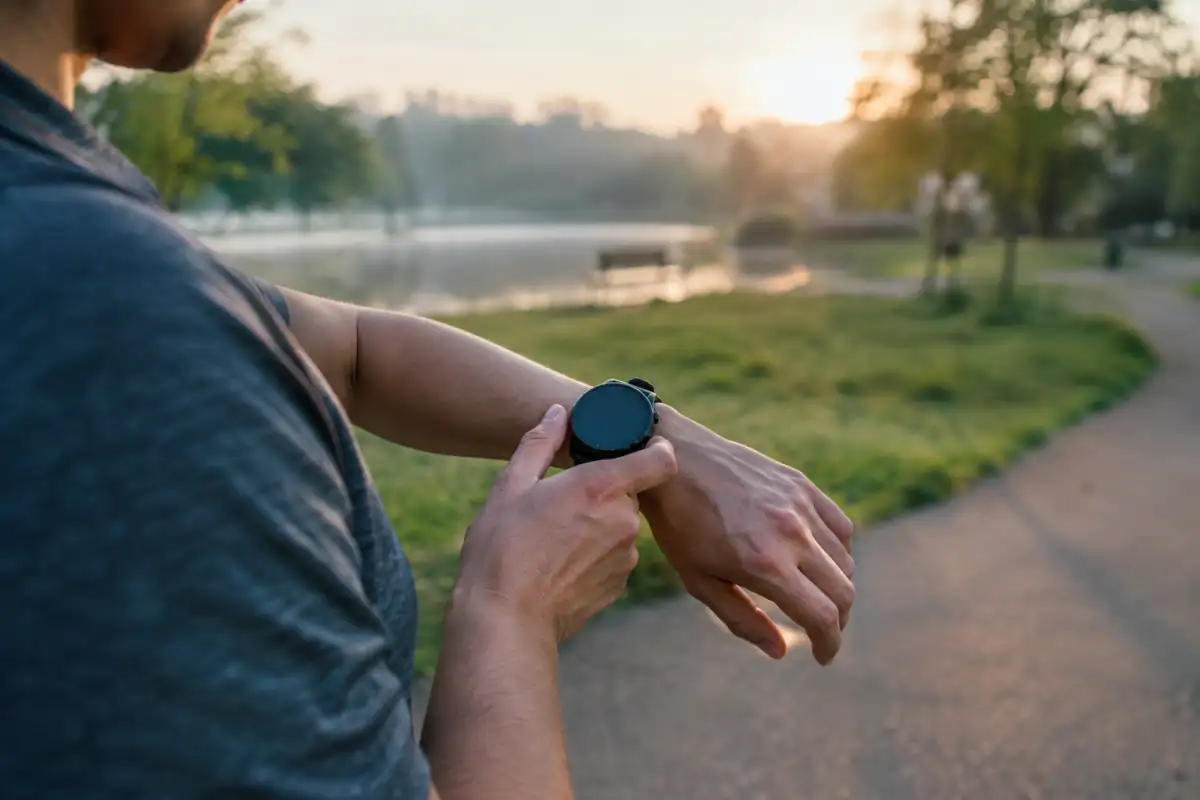 Coureur consultant sa montre cardio pendant une séance, pour suivre sa fréquence cardiaque et ses zones d’entraînement.