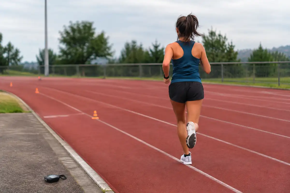 Coureur réalisant un test de six minutes sur une piste d’athlétisme, avec des plots de repérage et un chronomètre.