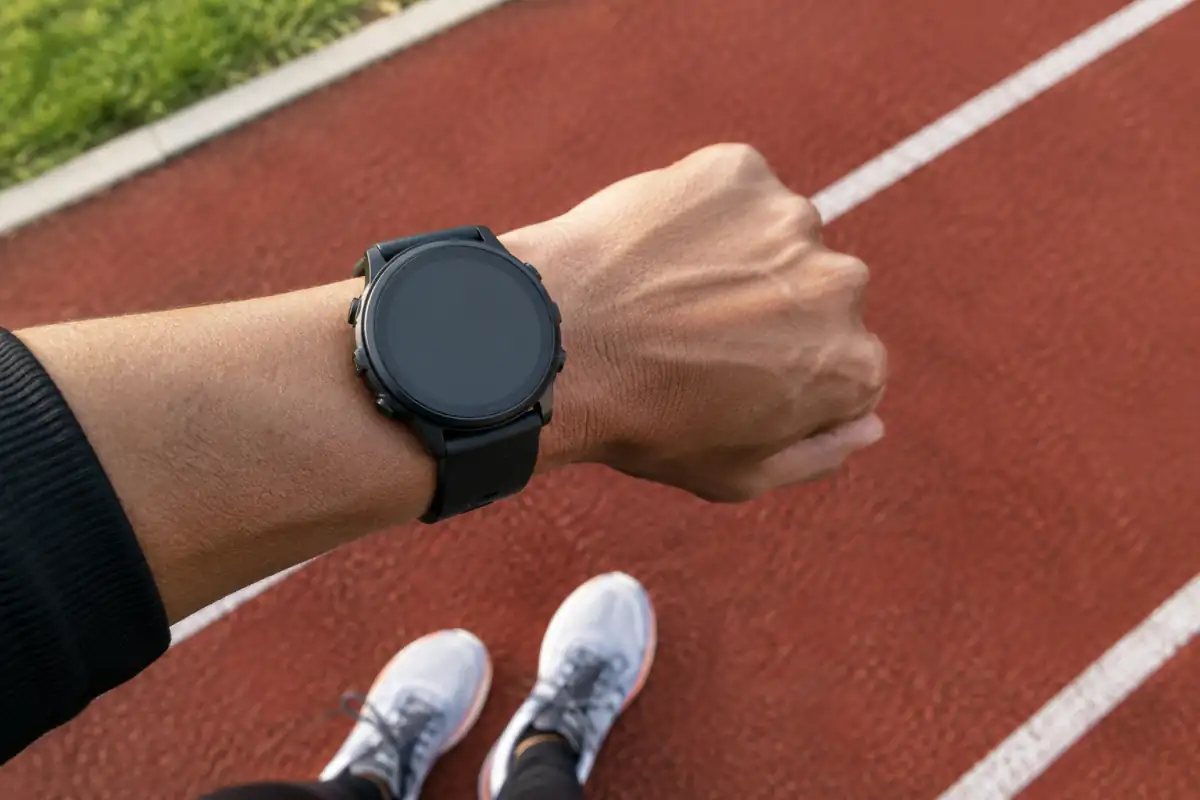Montre de course au poignet près d’une piste, pour illustrer le calcul de l’allure et des temps de passage.