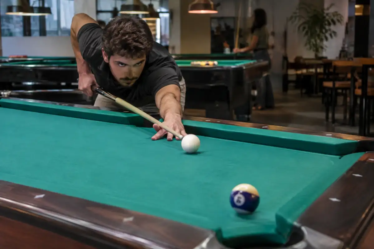 Joueur travaillant un coup droit au billard américain, blanche alignée vers une bille objet près d’une poche de coin.