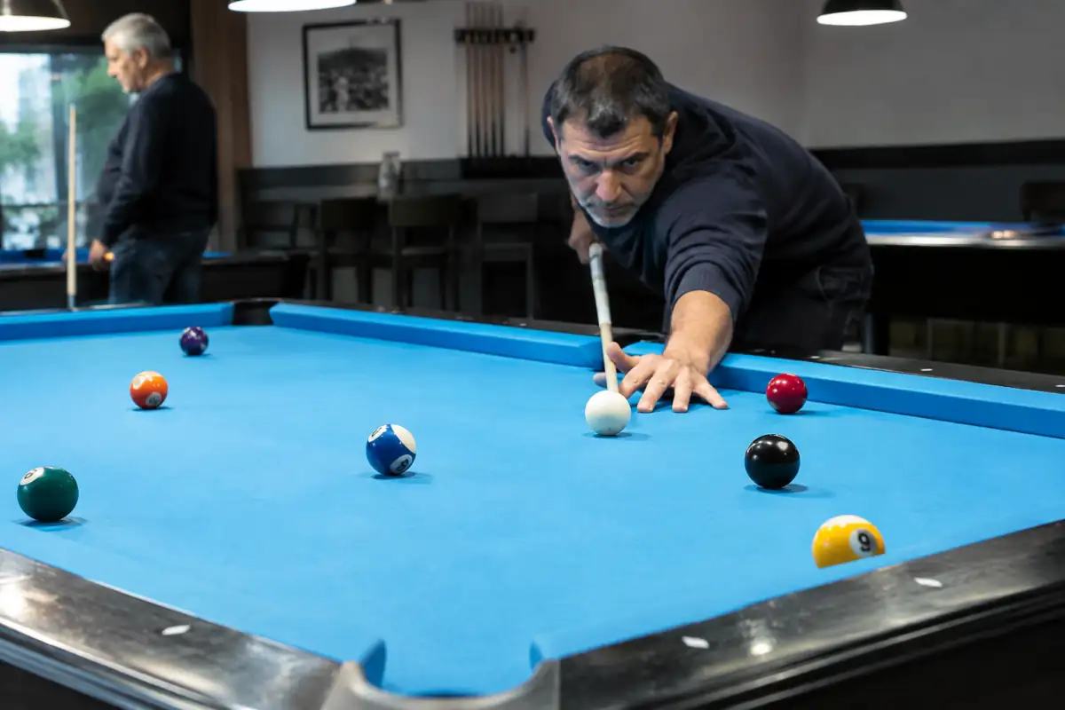 Joueur alignant la blanche sur la bille la plus basse au jeu de la 9, avec la bille 9 près d’une poche.