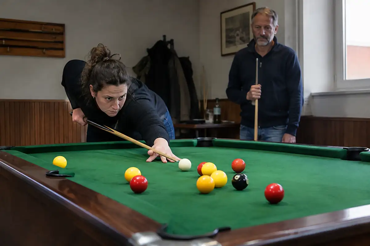 Un joueur vise la bille blanche sur une table de blackball avec des billes rouges, jaunes et la noire.
