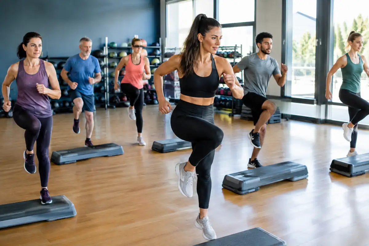 Un groupe suit un cours de BodyAttack en salle, avec un instructeur qui montre des déplacements cardio et des sauts contrôlés.