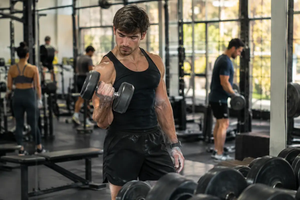 Un culturiste présente une pose de face sur scène lors d’une compétition de bodybuilding, devant les juges et les autres concurrents.