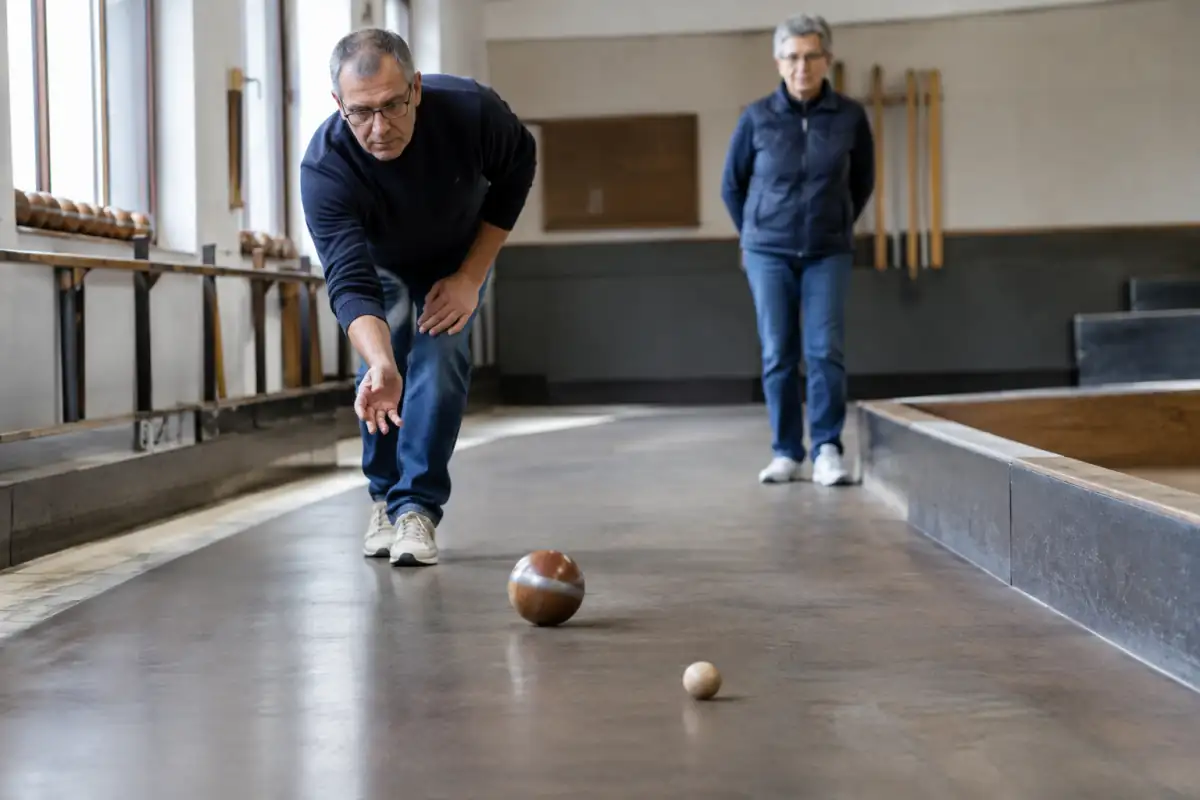 Un joueur fait rouler une boule de fort cerclée de métal sur la piste incurvée d’une société angevine.