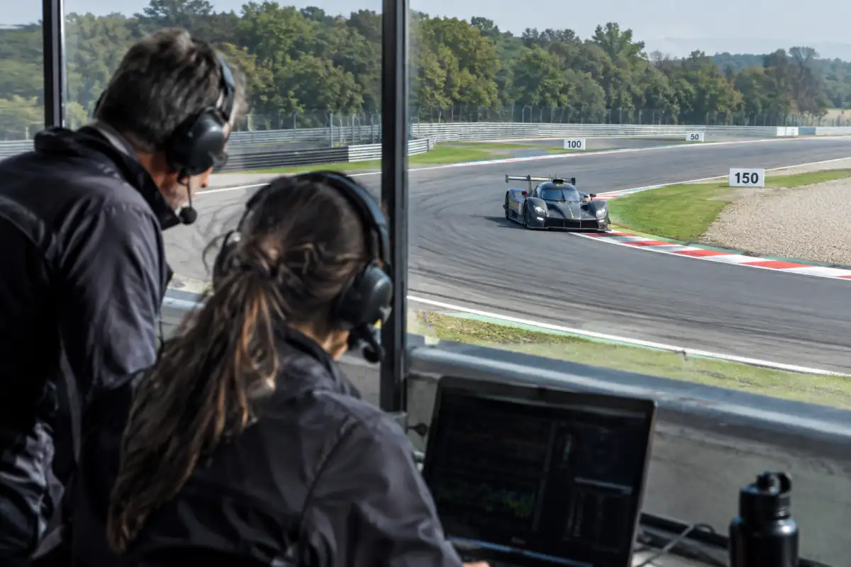 Voiture d’endurance en séance d’entraînement sur circuit, suivie depuis les stands par une équipe qui analyse les données de pilotage.