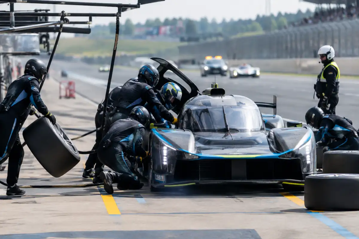 Arrêt aux stands d’une course d’endurance : mécaniciens coordonnés autour d’une voiture pendant un relais et un changement de pneus.