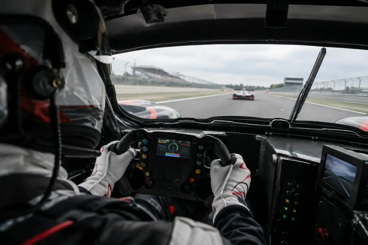 Depuis le cockpit d’une voiture d’endurance, un pilote écoute la radio et approche une autre voiture sur le circuit.