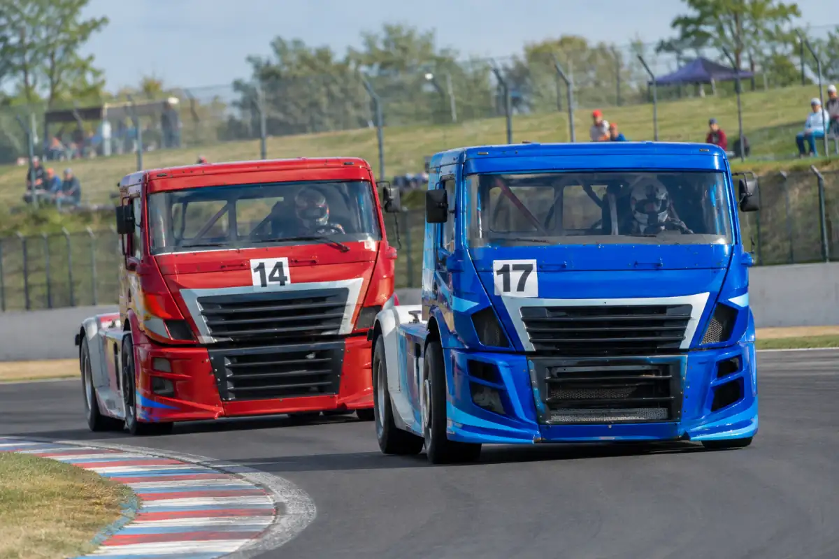 Course de camions sur un circuit français : deux poids lourds de compétition négocient un virage, cabines renforcées et vibreurs visibles.