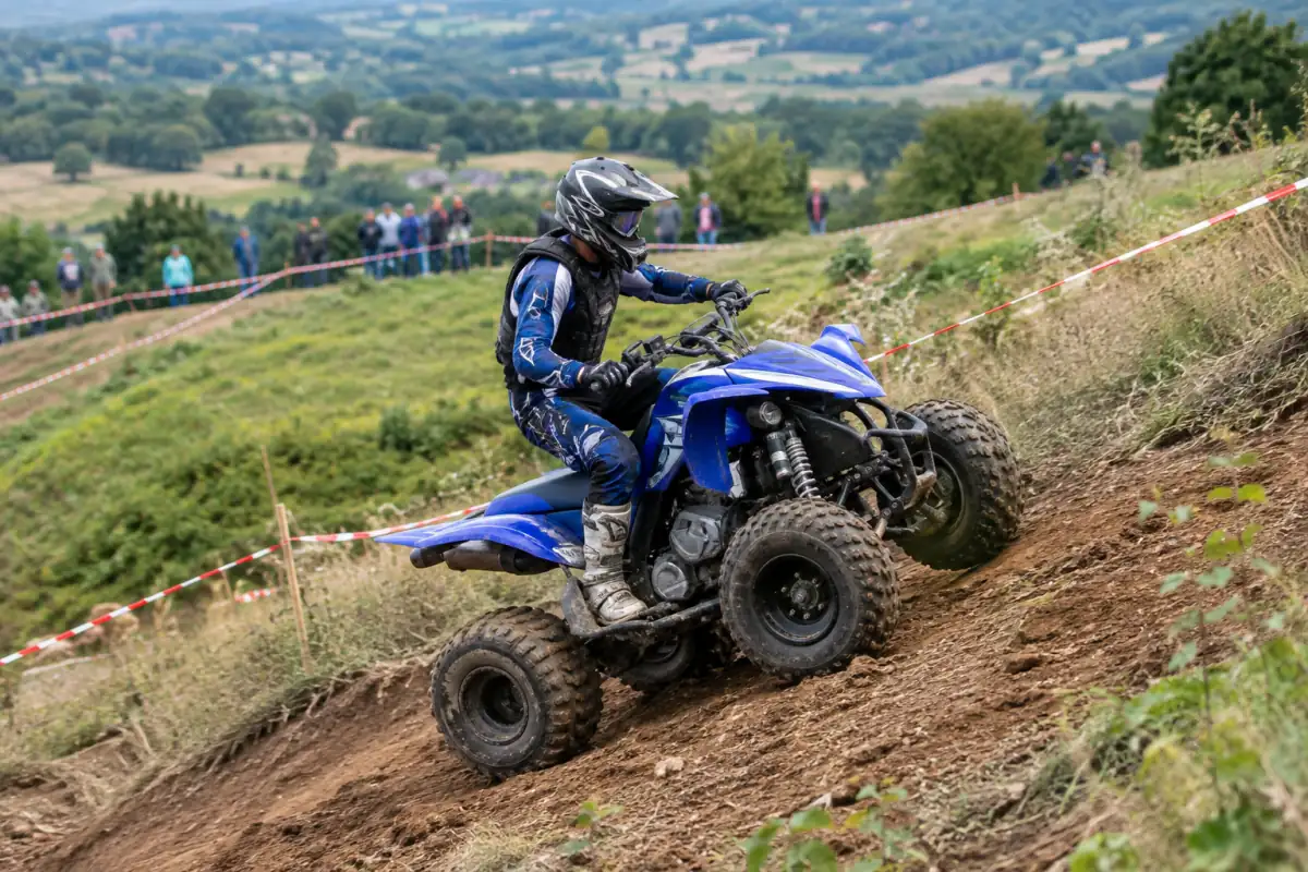 Pilote équipé gravissant une pente de terre sur un quad lors d’une course de côte, avec le parcours balisé.