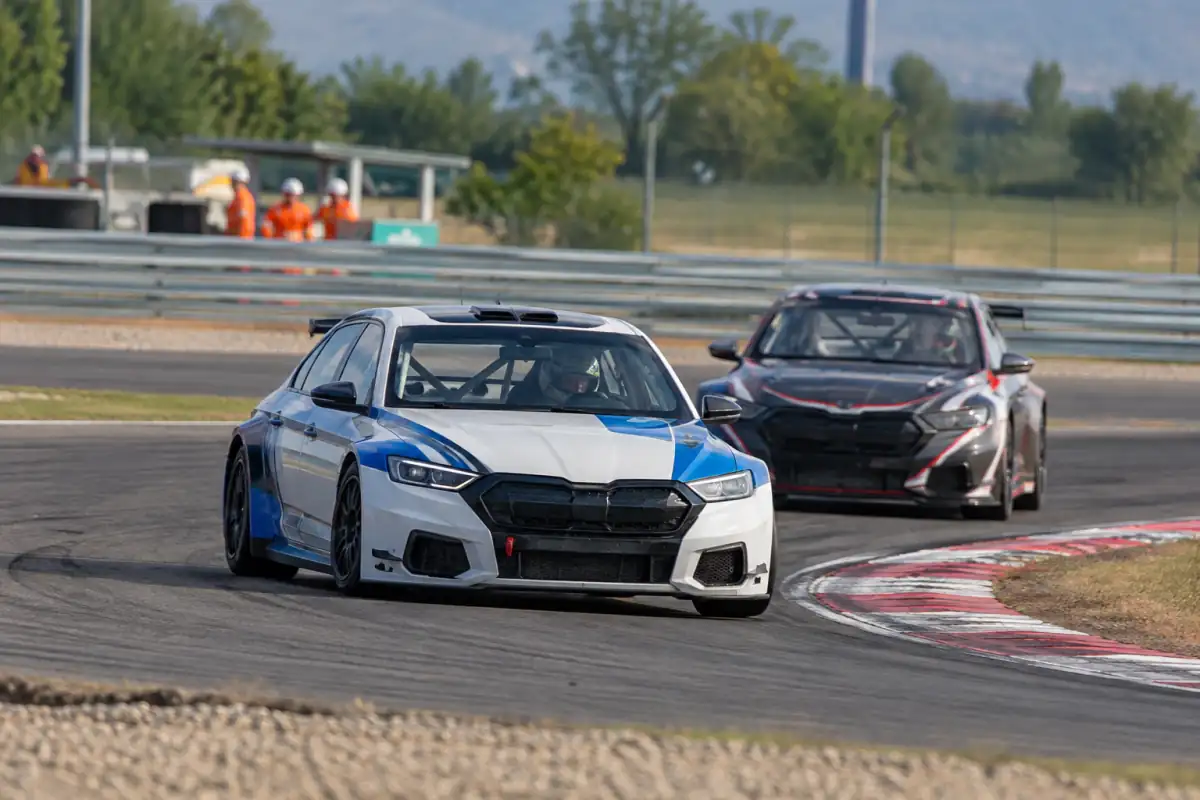 Voitures de tourisme de course négociant un virage serré sur circuit, avec pneus slicks et vibreurs au bord de la piste.