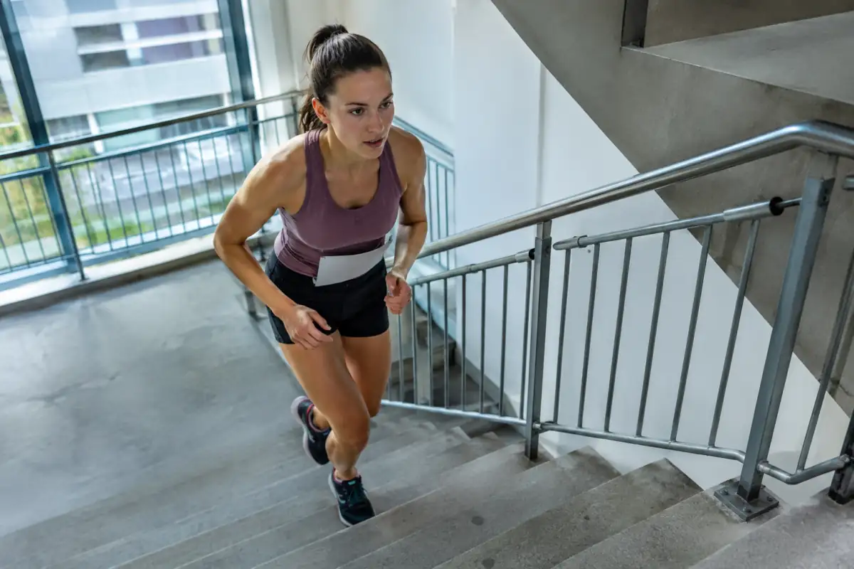 Un coureur en tenue légère gravit les marches d’un escalier de tour lors d’une course en escaliers chronométrée.