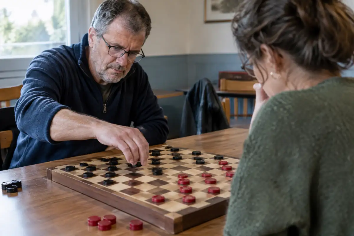 Partie de dames anglaises sur un damier de 8 × 8, où deux joueurs déplacent des pions en diagonale.
