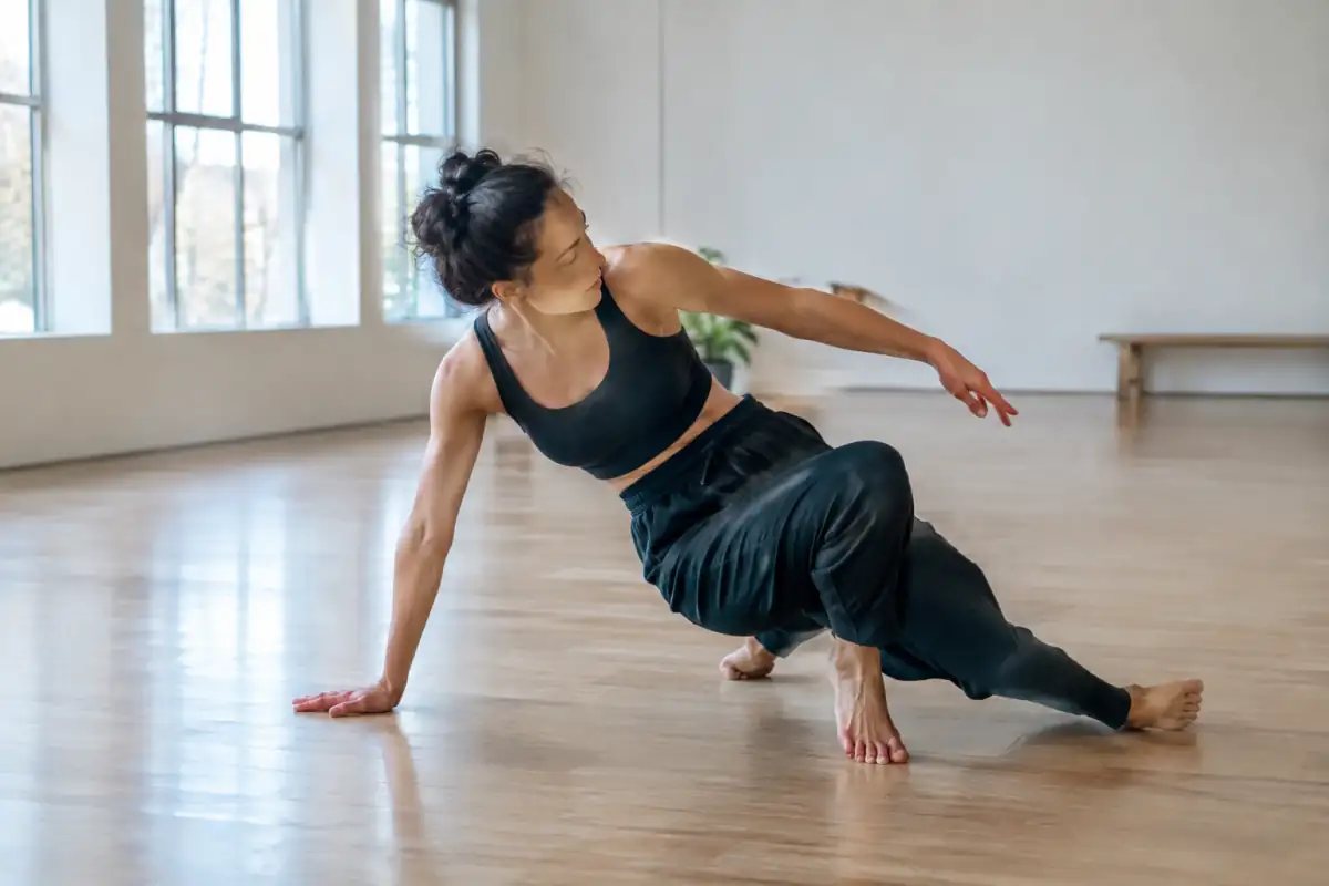 Danseuse en studio explorant une spirale au sol, une main en appui tandis que le buste tourne en opposition au bassin.