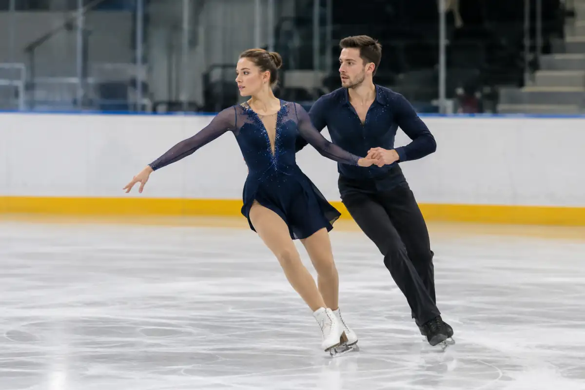 Couple exécutant une séquence de pas synchronisée en danse sur glace sur une patinoire intérieure.