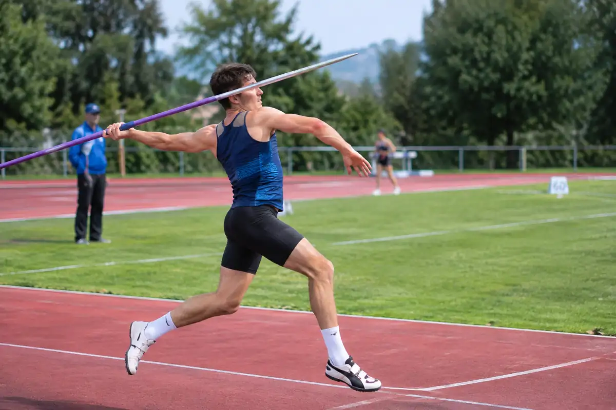 Un décathlonien lance le javelot sur la piste d’un stade d’athlétisme, lors d’une compétition en plein air.