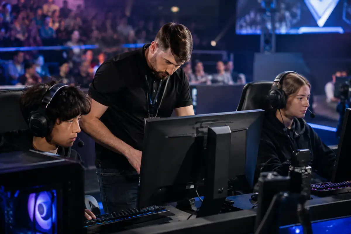 Un arbitre vérifie les postes et le déroulement d’une série de tournoi e-sport pendant que les joueurs attendent le match.