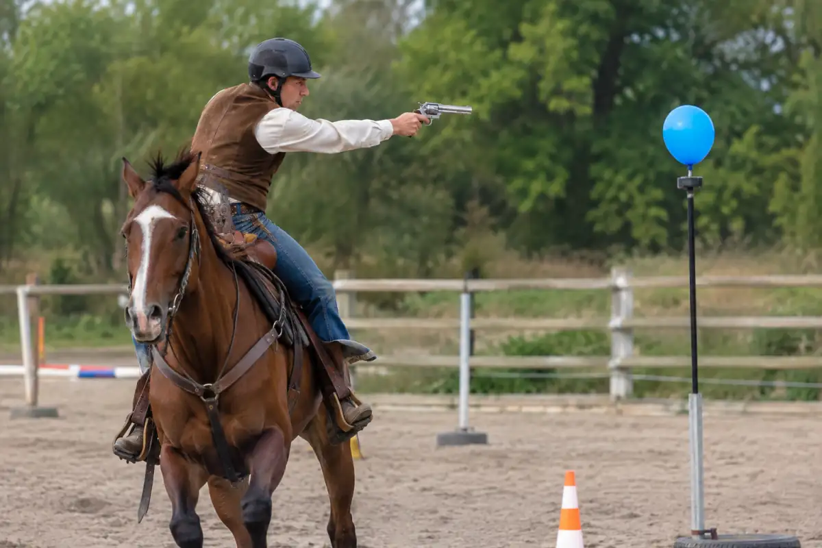 Équitation de tir monté : un cavalier en tenue western suit un parcours extérieur et vise une cible gonflable à cheval.