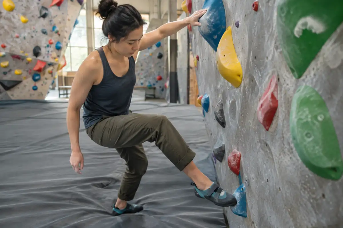 Une débutante travaille le placement précis de ses pieds sur un bloc facile, pendant une séance d’entraînement en salle.