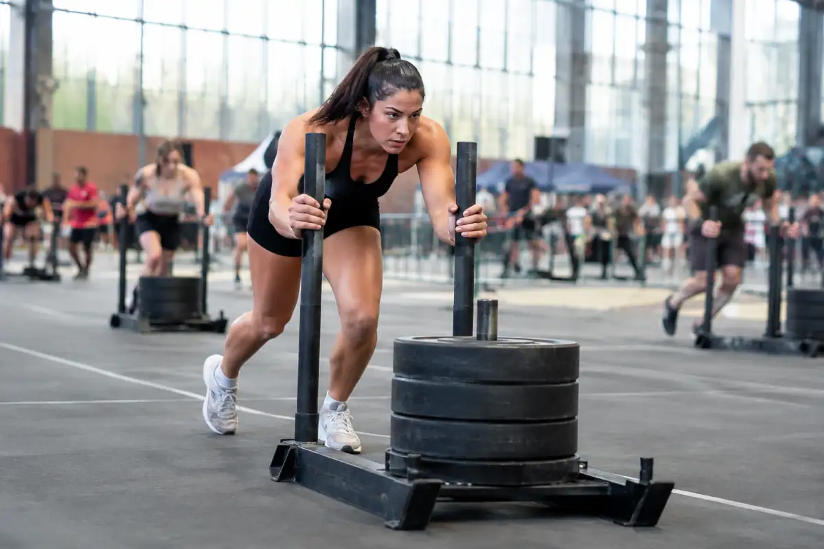 Un participant pousse un traîneau lesté dans une salle pendant une épreuve de fitness racing.