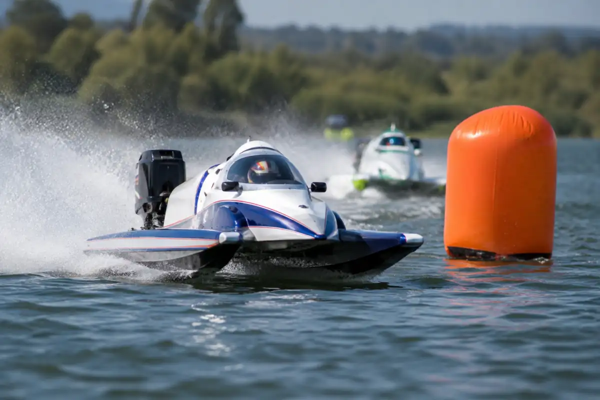 Pilote de Formule 1 motonautique en virage sur son catamaran de course à cockpit protégé, au milieu des gerbes d’eau.