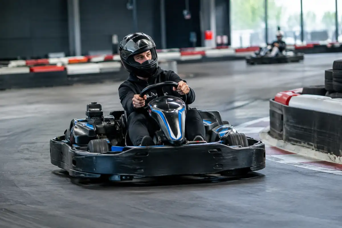 Pilote amateur en karting regarde la sortie d’un virage et suit une trajectoire régulière sur une piste balisée.