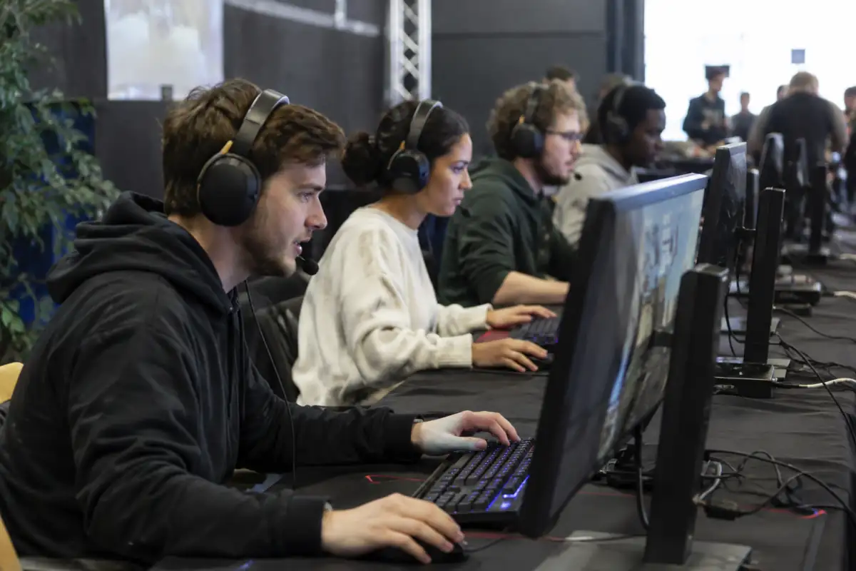 Joueurs d’une équipe de FPS en esport concentrés sur leurs écrans lors d’une compétition en salle.