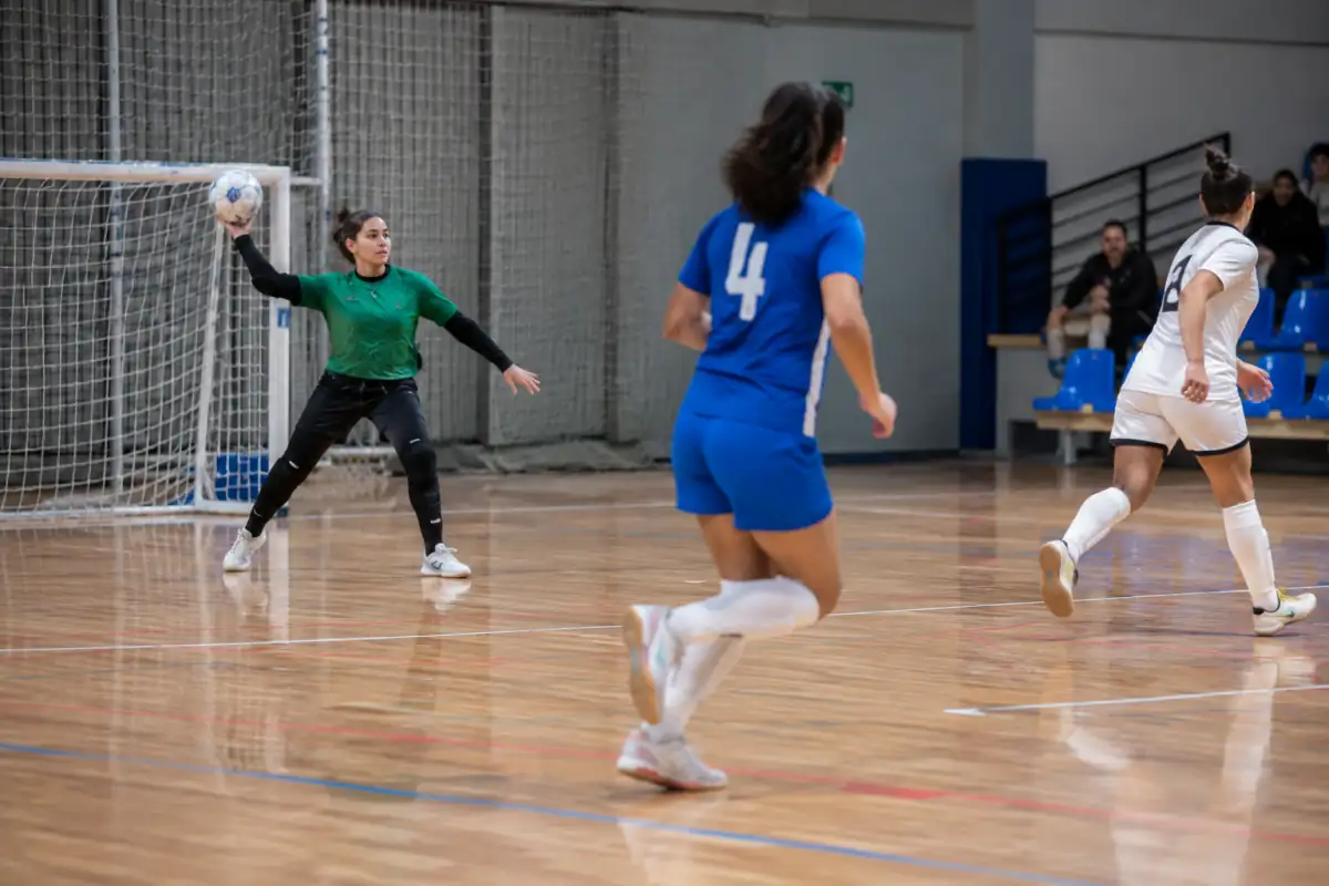 Un gardien de futsal effectue une relance à la main depuis sa surface pendant que les joueurs se replacent sur le terrain.