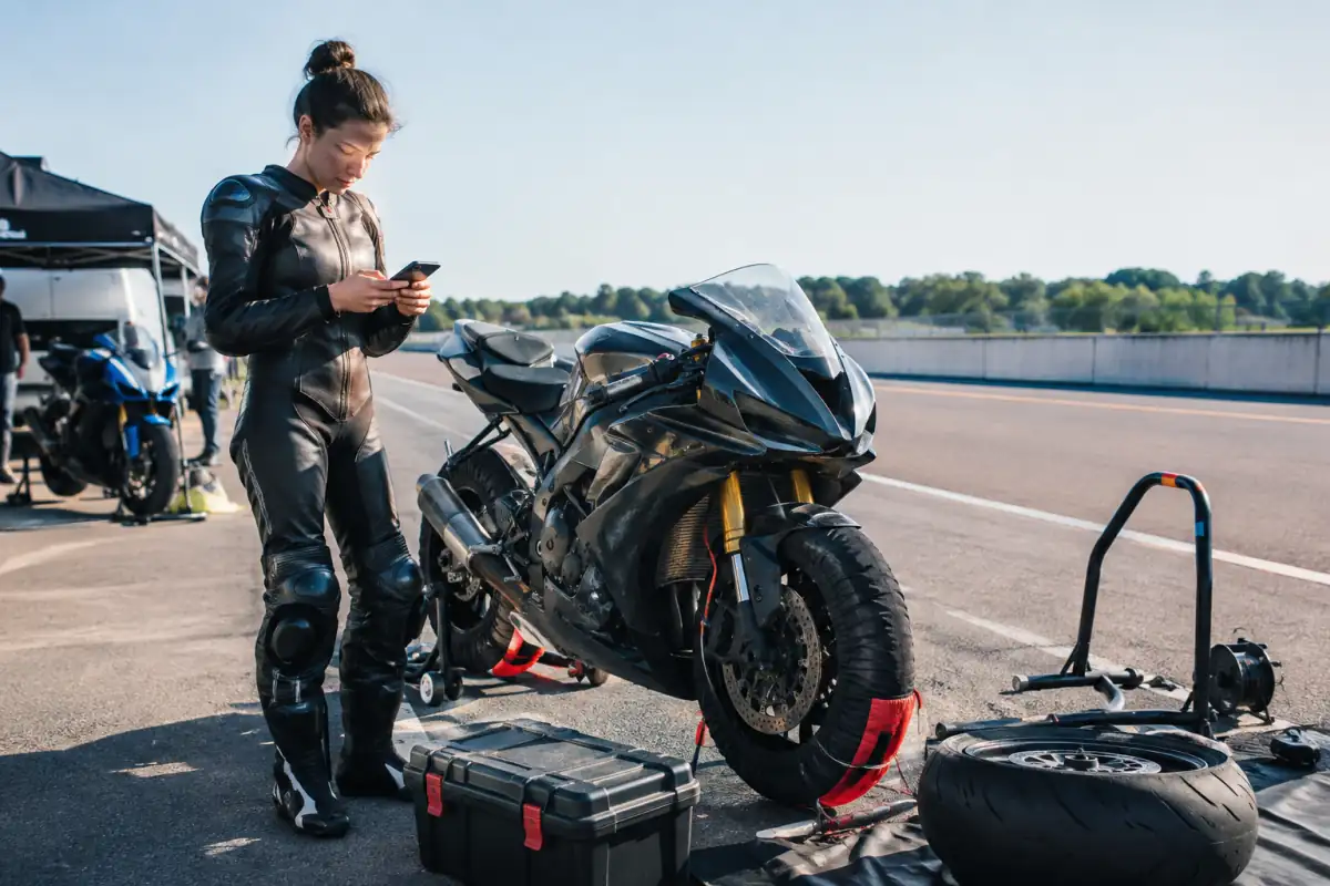 Motard débutant équipé près d’une moto de piste d’occasion, avec pneus et outils préparés pour estimer le budget de saison.