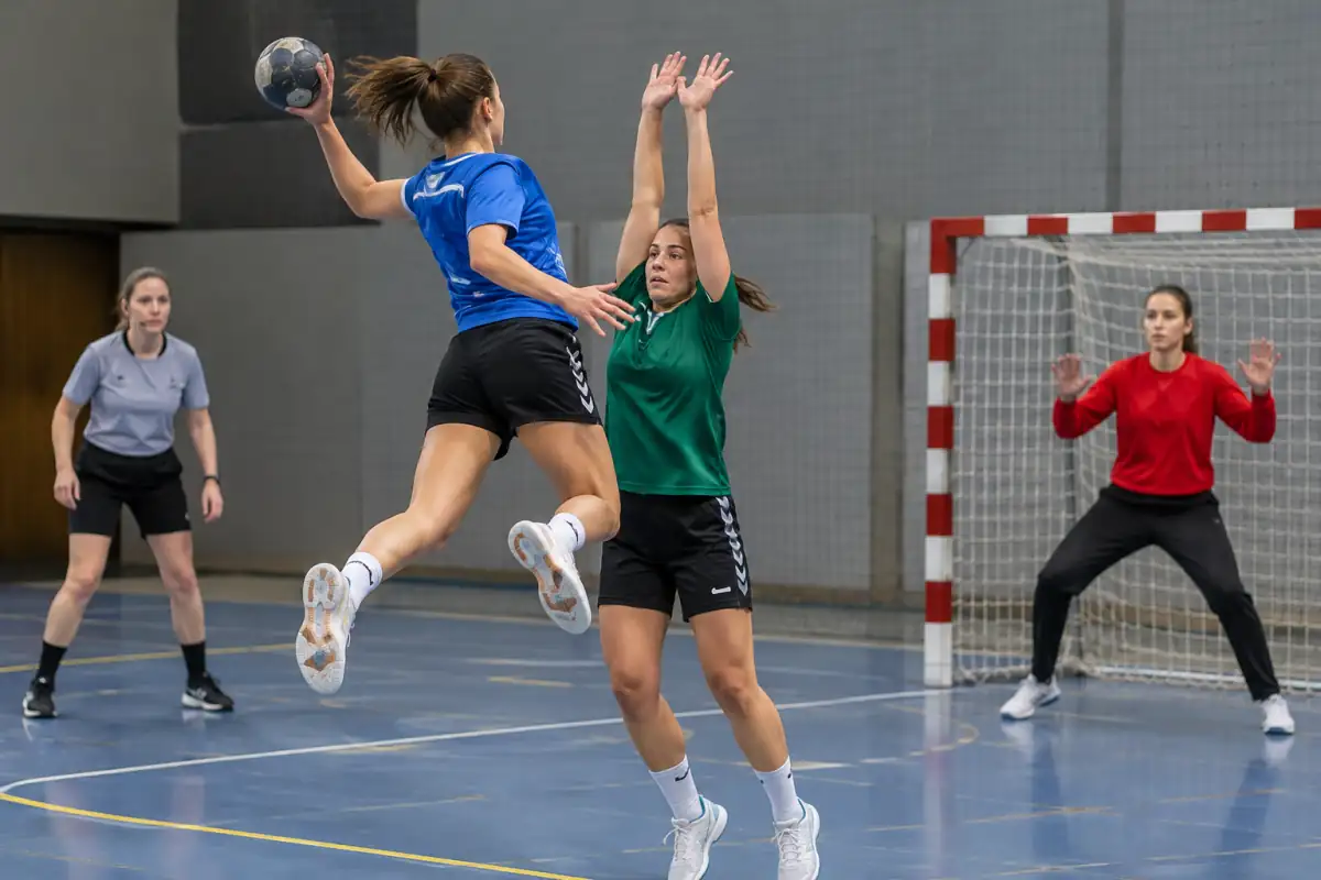 Tir en suspension au handball : l’attaquant lâche le ballon avant de retomber dans la zone des 6 mètres, sous le regard de l’arbitre.