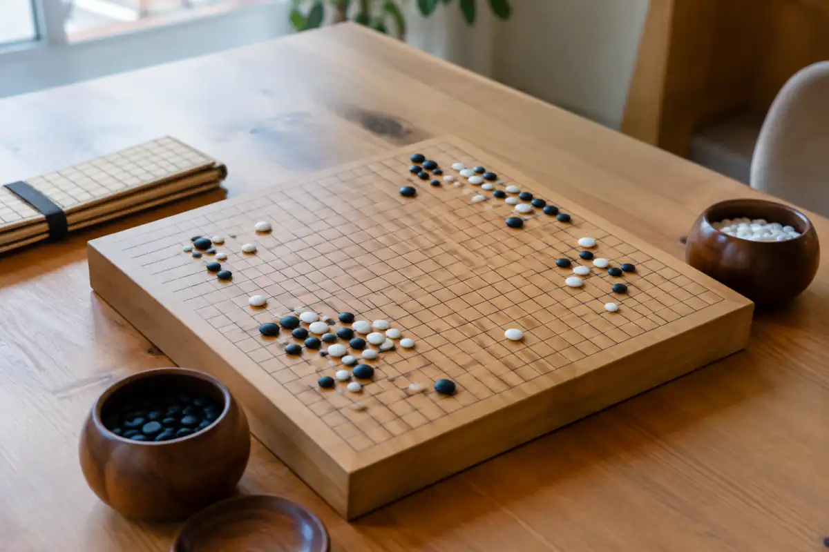 Goban en bois 19×19 avec pierres de verre et bols, accompagné d’un plateau pliant de voyage pour comparer les formats.
