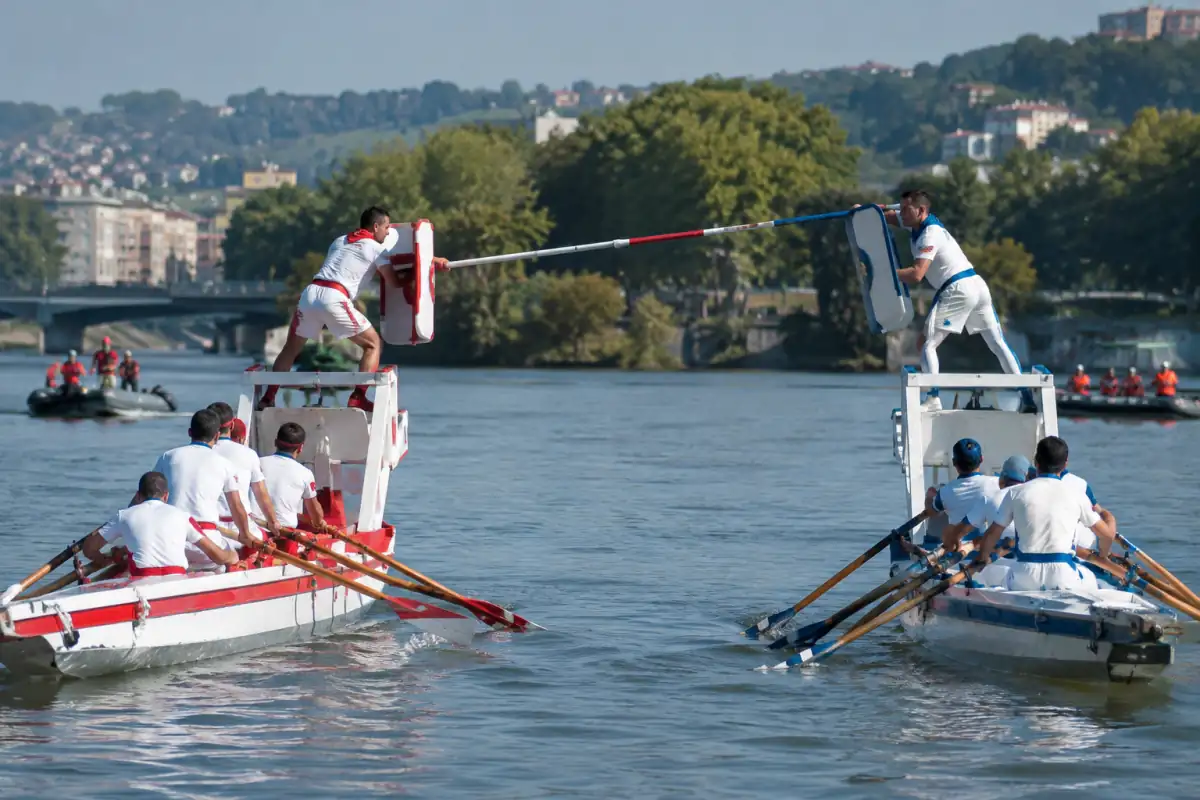 Joute lyonnaise sur le Rhône : un jouteur debout sur le tabagnon repousse la lance adverse depuis sa barque.