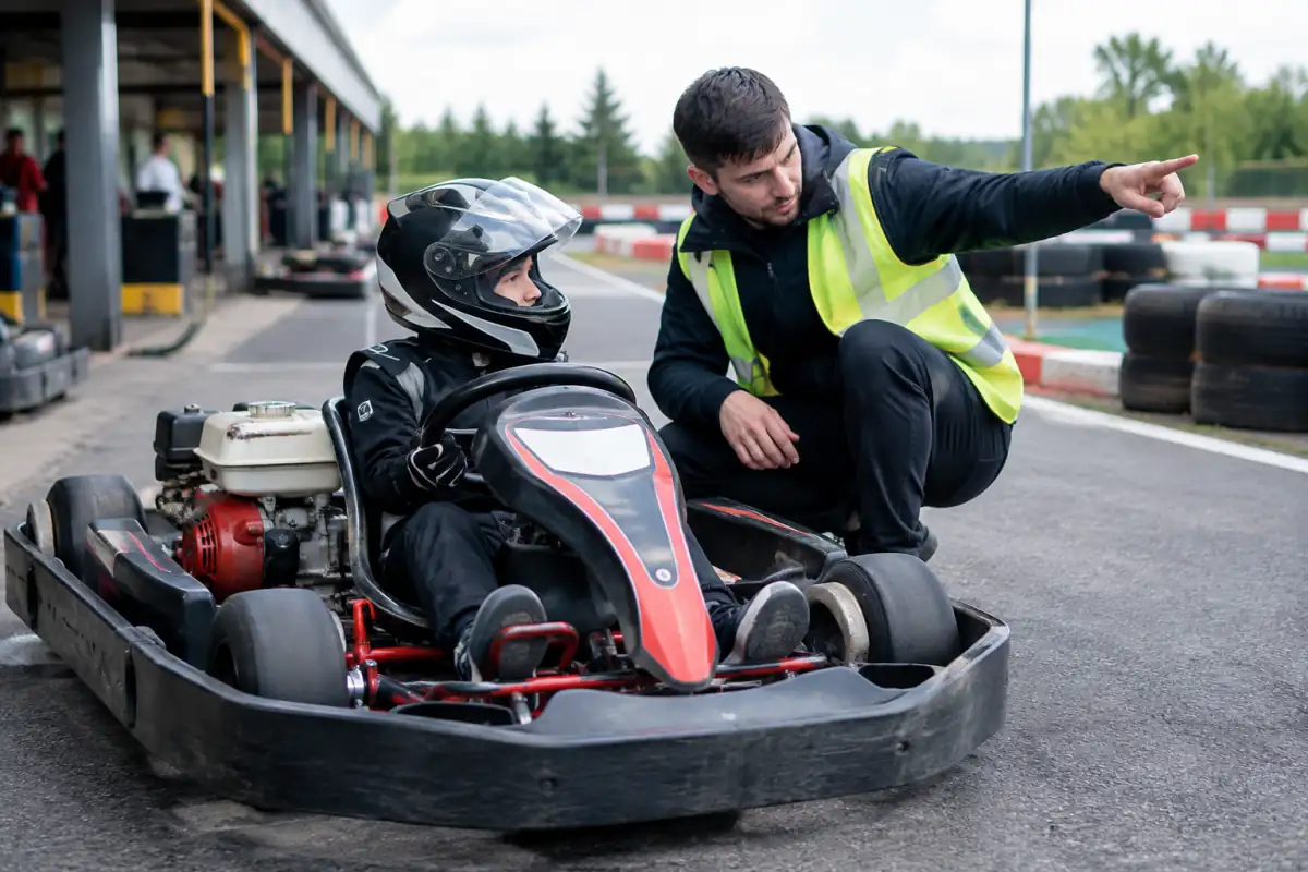 Un jeune débutant écoute le briefing d’un moniteur avant sa première séance de karting sur une piste française.