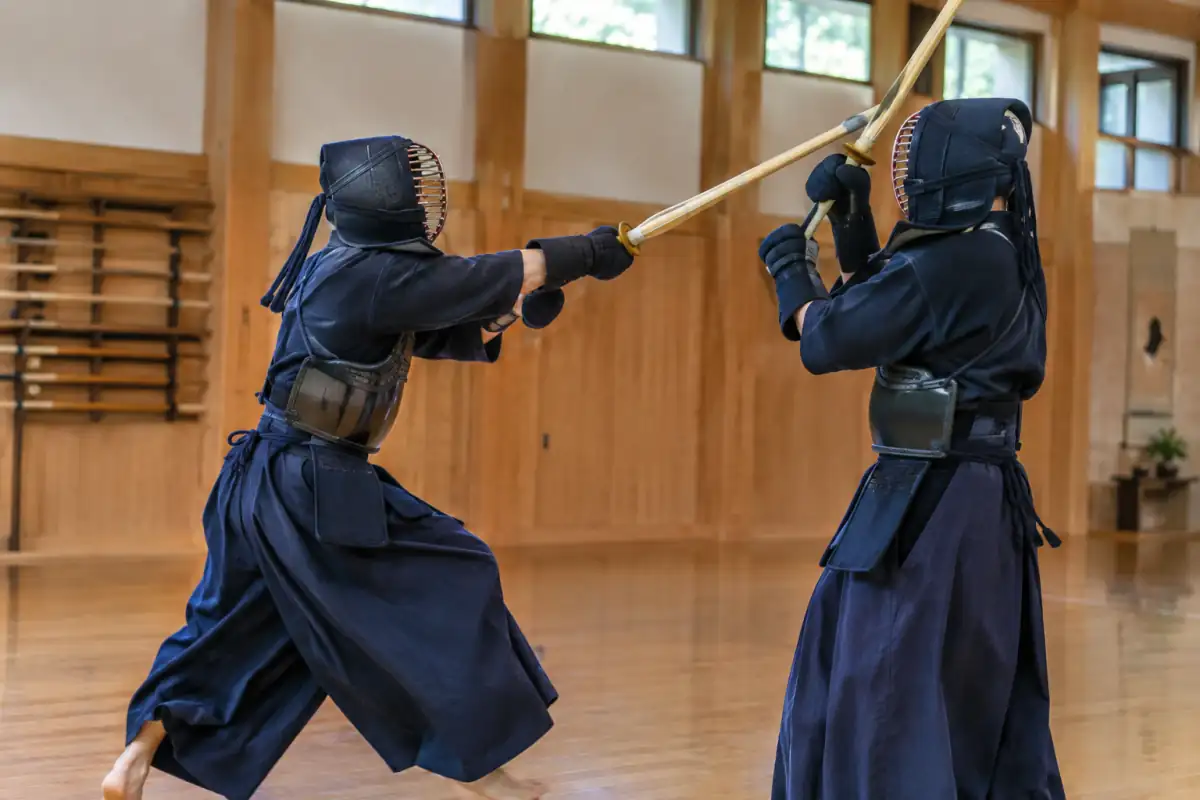 Deux kendokas en armure s’affrontent au shinai dans un dojo, lors d’un échange de kendo en France.