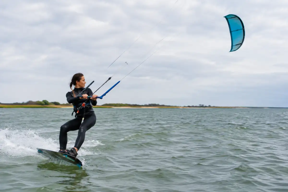Kitesurfeur débutant en appui sur la carre arrière, aile stabilisée et regard orienté vers sa trajectoire au vent.