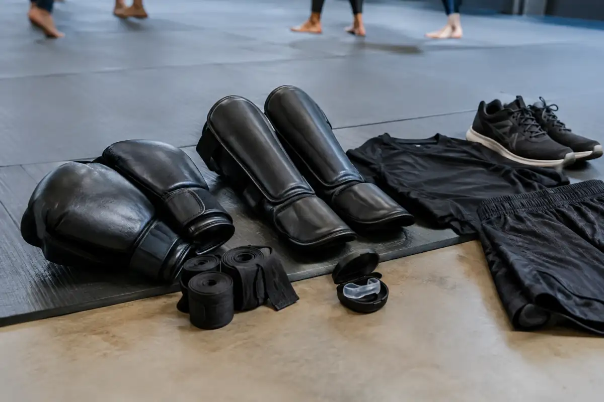 Gants fermés, bandes, protège-tibias et protège-dents réunis sur un tatami pour préparer un premier cours de krav-maga.