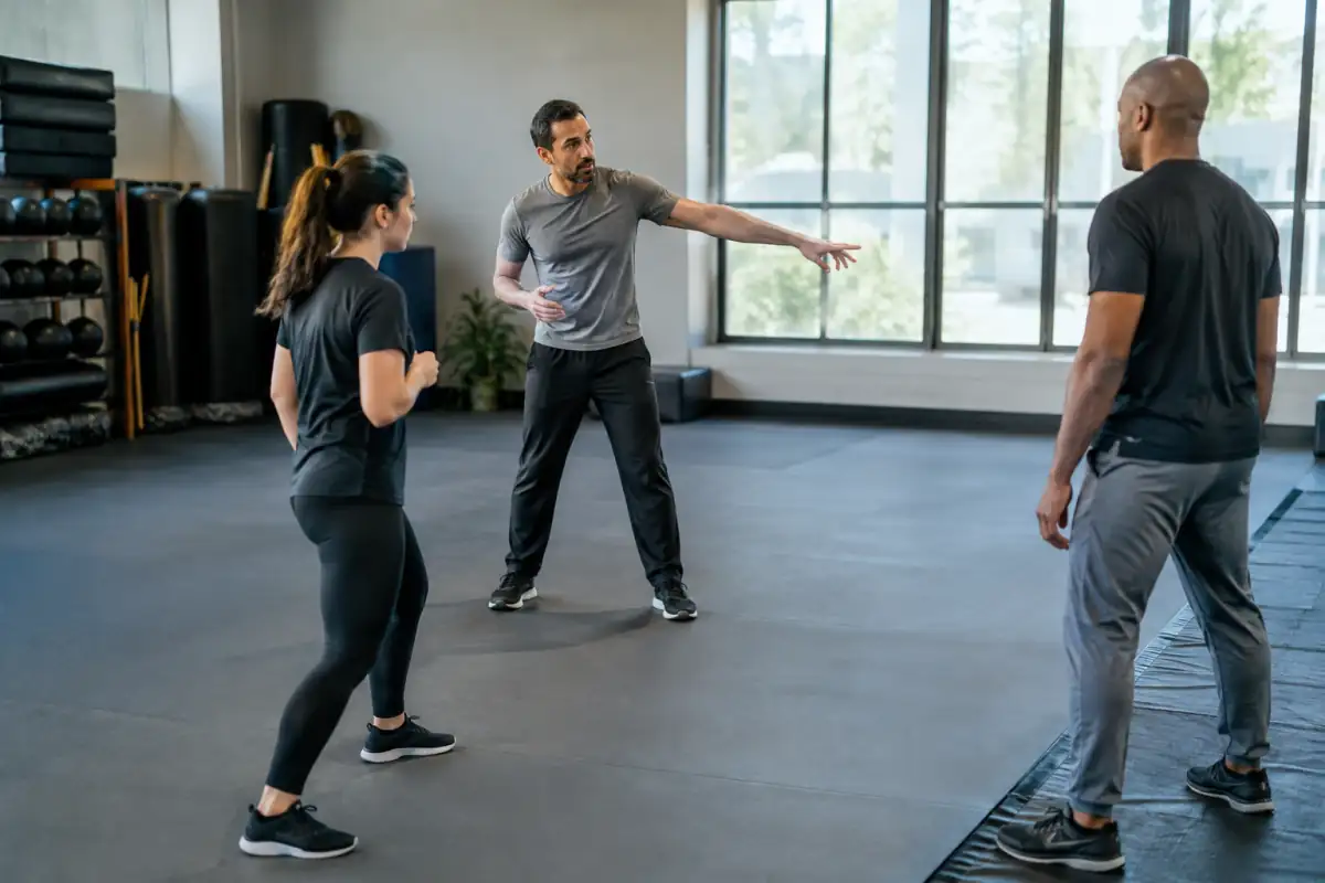 Débutants en krav-maga travaillant l’attention et le repérage d’une sortie dans une salle d’entraînement encadrée.