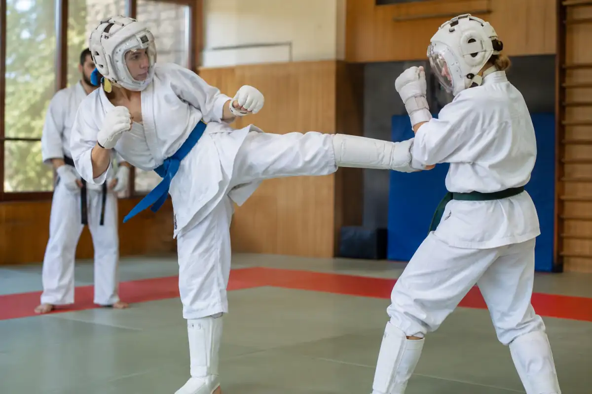 Deux pratiquants de Kudo en assaut encadré, équipés de casques à visière et de protections sur un tatami.