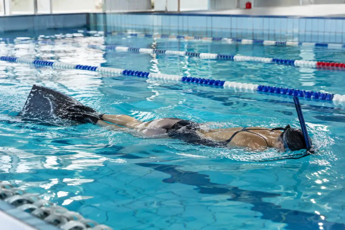 Nage avec palmes en piscine : un nageur équipé d’une monopalme et d’un tuba frontal avance en ondulant.