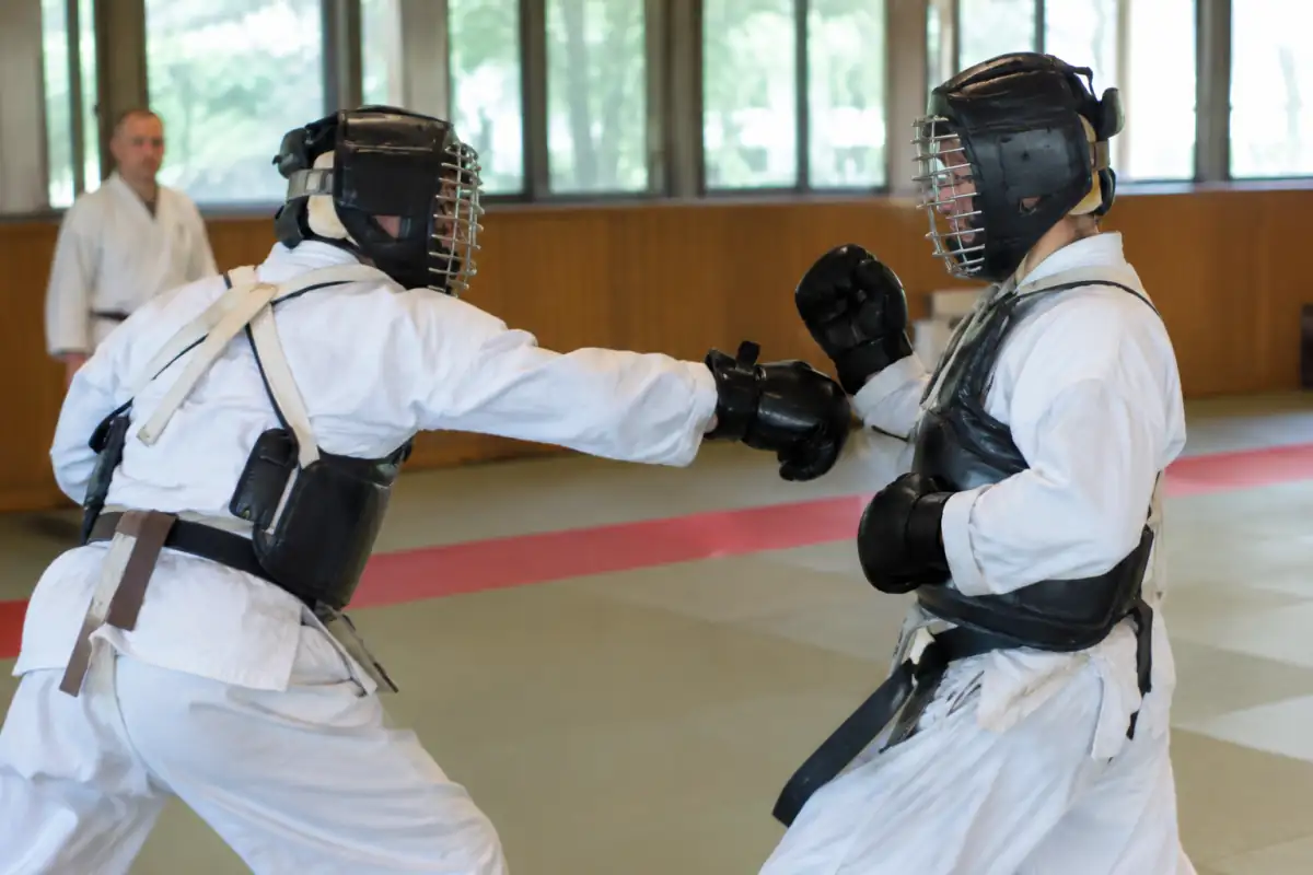 Combat de nippon kempo en dojo : deux pratiquants équipés de leur casque, de gants et d’un plastron travaillent une frappe contrôlée.