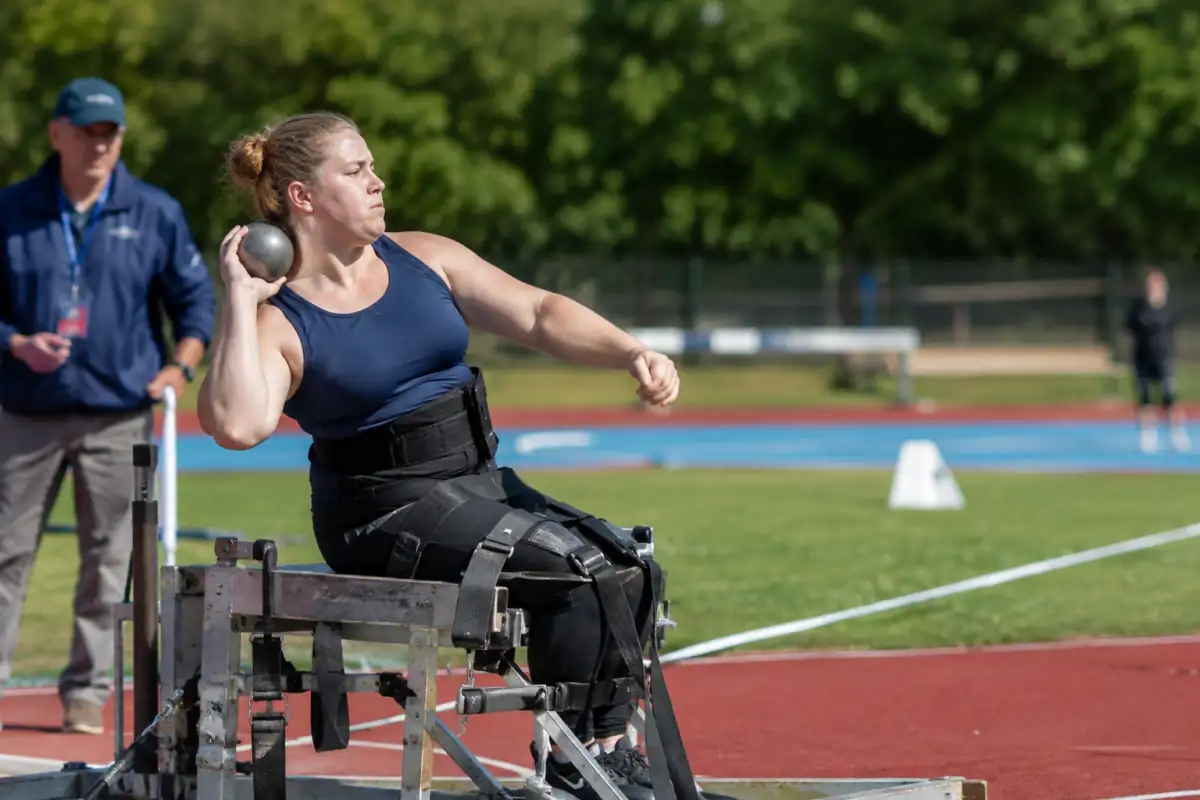 Lancer de poids assis en para-athlétisme, avec un athlète installé dans un cadre réglementaire et le secteur de chute visible.