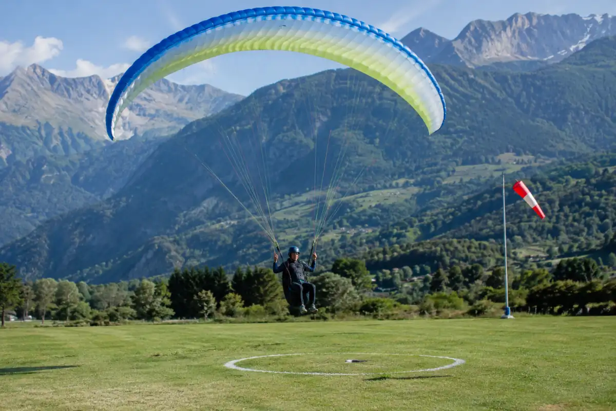Un pilote en parapente de précision ajuste son approche vers une cible électronique sur une aire d’atterrissage alpine.