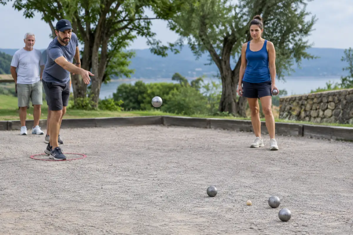 Un joueur prépare une boule portée vers le but pendant que son partenaire observe les boules adverses sur le terrain.